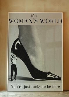 a woman's world poster on the wall next to a lamp