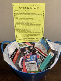 a birthday survival kit sits in a bucket on a table with a sign above it