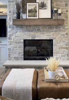 a living room with stone fireplace and built - in entertainment center, coffee table and ottoman