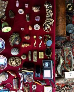 a red velvet covered table topped with lots of different types of jewelry and knick knacks