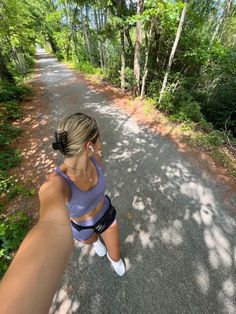 a woman is taking a selfie in the middle of a road with trees on both sides