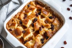 a casserole dish filled with bread and raisins on a white table