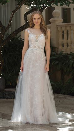 a woman standing in front of a tree wearing a wedding dress