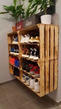 a wooden shoe rack with many pairs of shoes on it and a potted plant in the corner