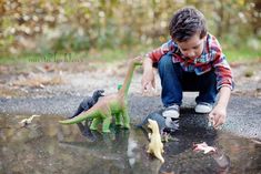 a young boy playing with toy dinosaurs in the rain