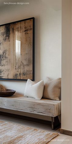 a wooden bench sitting in front of a painting on the wall next to a rug