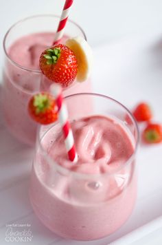 two glasses filled with pink smoothie and strawberries