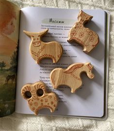 three wooden animals are sitting on top of an open book