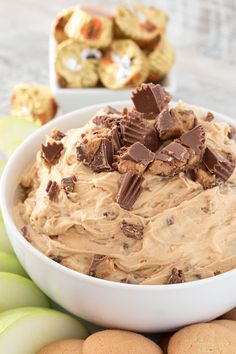 a white bowl filled with peanut butter and chocolate chips next to some cookies on a table