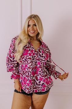 - Let your bubbly personality shine through with this beautiful top! - Unlined material with pink, blue, and purple hues and tangerine highlights - An abstract floral print as well as a subtle striped pattern - A ruffled v-cut neckline with a tie detail - Pleated shoulder details - Long, loose sleeves with smocked ruffle cuffs - Pleated detail - A relaxed silhouette that ends in a straight hemline Feminine Purple Top With Floral Print, Feminine Pink Printed Top, Pink Bohemian Blouse With Vibrant Print, Pink V-neck Top With Vibrant Print, Bohemian Pink Blouse With Vibrant Print, Vibrant Pink V-neck Top, Spring Mauve Tops With Floral Print, Pink V-neck Blouse With Vibrant Print, Purple Cotton Blouse With Floral Print