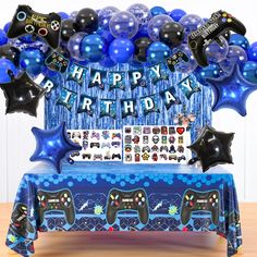 a birthday party with balloons, streamers and video game controllers on a blue table cloth