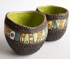 two ceramic bowls with designs on them sitting next to each other in front of a white background