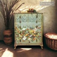 an old dresser with flowers painted on it next to two baskets and a wicker basket