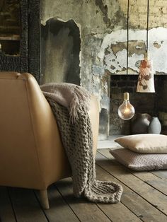 a living room filled with furniture and a fire place next to a wall covered in peeling paint