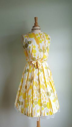 Now that's a cocktail dress! 🍸🍋 This vintage dress looks like an olive martini with a citrus twist, with its fun abstract dot and stem print, bursting with pops of orange, yellow and green on a cream background. It features a blouson-style bodice that buttons in the back; a cinched waist accented by a matching tie sash; and a full, twirly pleated skirt. (Pictured with a crinoline- not included - to demonstrate fullness; its white edge peeks out at the hem.) Bodice is lined; back metal zip at w Summer Garden Party Dress With Box Pleat, Summer Dresses With Box Pleat And Full Skirt, Fitted Pleated Skirt Dress For Garden Party, Fitted Dress With Pleated Skirt For Garden Party, Yellow Pleated Dress For Cocktail, Yellow Pleated Dress For Cocktail Occasions, Green Retro Cocktail Dress, Vintage Green Pleated Dress, Retro Spring Dress With Pleated Waist