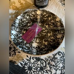 a bottle of wine sitting on top of a glass plate next to a skull print table cloth