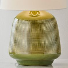 a green lamp with a white shade on it's base and a light bulb in the middle