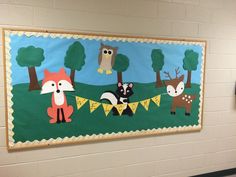 an animal themed bulletin board hangs on the wall in a school hallway, decorated with animals and pennants