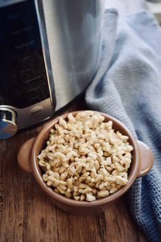 a bowl filled with rice next to an air fryer on top of a wooden table