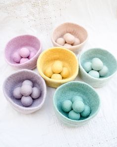 four bowls filled with colored eggs on top of a table