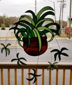 a hanging planter made out of stained glass on a wooden rail next to a street