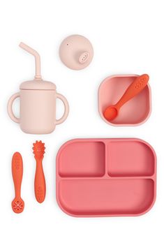 a pink tray with utensils, spoons and cup next to it on a white surface