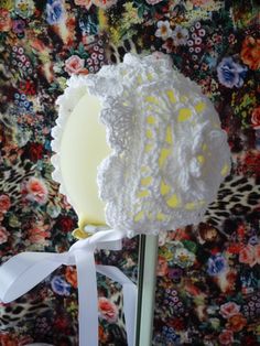 a white crocheted flower on top of a metal pole with a ribbon around it