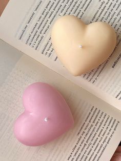 two heart shaped candles sitting on top of an open book