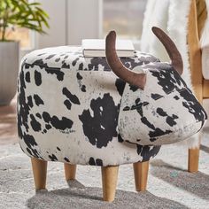 a cow - like footstool with wooden legs on carpeted floor