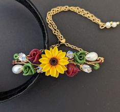 a yellow sunflower with red roses and pearls on a black velvet choker necklace