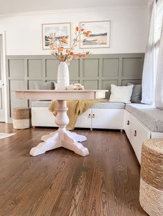 a white table sitting on top of a hard wood floor next to a bed in a bedroom