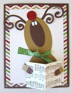 a christmas card with a reindeer holding a sheet of paper and an ornament