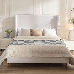 a bed with white linens and pillows in a small bedroom area, along with two nightstands