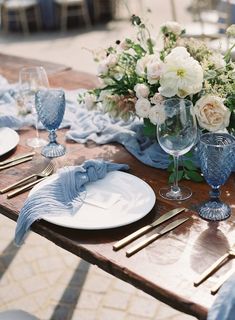 the table is set with blue and white plates, napkins, silverware, and flowers