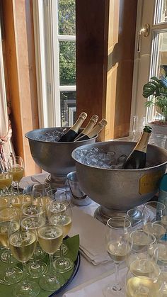 there are many glasses on the table with wine in them and champagne bottles near by