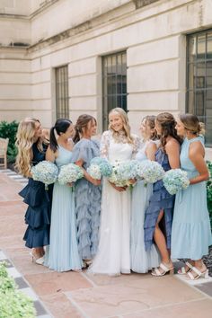 a group of women standing next to each other in front of a building with flowers