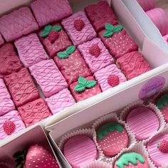 two boxes filled with pink and green decorated cookies next to strawberries on top of each other