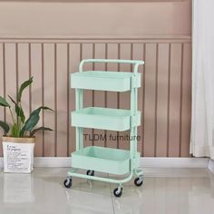 a green cart sitting on top of a floor next to a potted plant