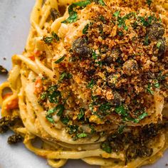 a close up of a plate of food with noodles and sauce on it, topped with parmesan crumbs