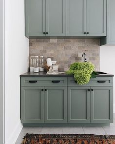 a kitchen with green cabinets and a rug on the floor