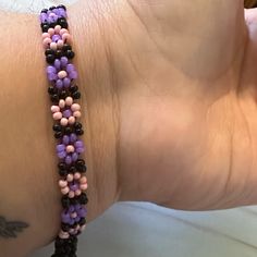 a woman's arm with a purple and black beaded bracelet on it