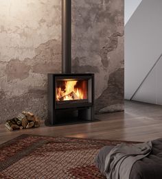 a wood burning stove in a living room next to a pile of logs and a rug