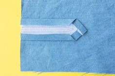 a piece of blue fabric with white stitching on it and a yellow strip next to it