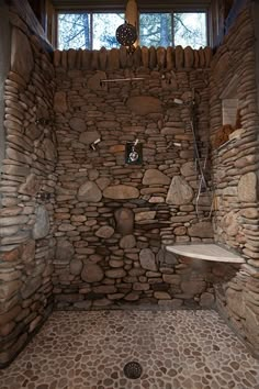 a bathroom with stone walls and flooring in the shower area, along with a window