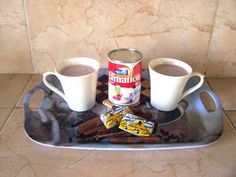 two cups of coffee sit on a tray