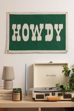 a record player sitting on top of a wooden table next to a green sign that says howdy