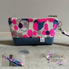 the zippered pouch is decorated with pink, blue and gray flowers on it's side