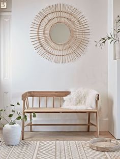 a wooden bench sitting next to a white wall with a mirror on the wall above it