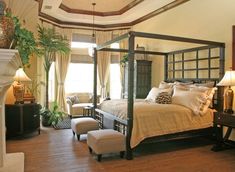 a bedroom with a four poster bed sitting next to a chair and ottoman on top of a hard wood floor