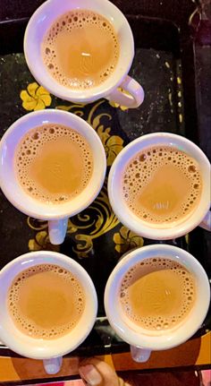 four cups of coffee sitting on top of a tray